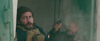 Movie still from “The Covenant” (2023), directed by Guy Ritchie – A man holding a gun in front of another man; Close Up shot, Over the shoulder angle