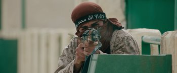 Movie still from “The Covenant” (2023), directed by Guy Ritchie – A man with a gun wearing a head scarf; Medium shot, Low angle