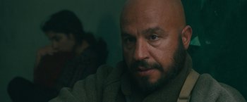 Movie still from “The Covenant” (2023), directed by Guy Ritchie – A man with a beard is looking at the camera; Close Up shot, Over the shoulder angle