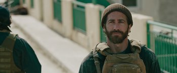 Movie still from “The Covenant” (2023), directed by Guy Ritchie – A man with a beard wearing a hat and a backpack; Close Up shot, Over the shoulder angle