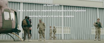 Movie still from “The Covenant” (2023), directed by Guy Ritchie – A group of people standing next to each other on a field; Wide shot, Over the shoulder angle