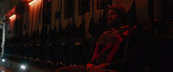 Movie still from “The Covenant” (2023), directed by Guy Ritchie – A man sitting in a chair in the dark; Medium shot, Over the shoulder angle