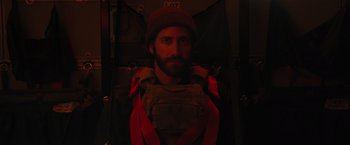 Movie still from “The Covenant” (2023), directed by Guy Ritchie – A man with a beard wearing a vest and a hat; Close Up shot, Low angle