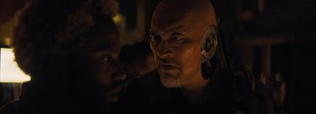 Movie still from “The Creator” (2023), directed by Gareth Edwards – A man with a bald head wearing a headset; Close Up shot, Over the shoulder angle