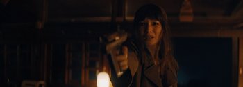 Movie still from “The Creator” (2023), directed by Gareth Edwards – A woman holding a gun in a dimly - lit room; Close Up shot, Low angle