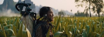 Movie still from “The Creator” (2023), directed by Gareth Edwards – A man in a field with headphones on his ears; Close Up shot, Over the shoulder angle