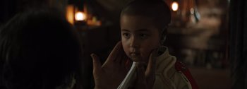 Movie still from “The Creator” (2023), directed by Gareth Edwards – A young child is holding his head with his hands; Close Up shot, Over the shoulder angle
