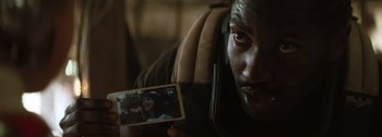 Movie still from “The Creator” (2023), directed by Gareth Edwards – A man holding up a picture of a woman in front of his face; Close Up shot, Over the shoulder angle