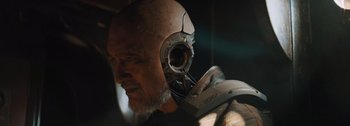 Movie still from “The Creator” (2023), directed by Gareth Edwards – An older man with a beard and a helmet on his head; Close Up shot, Low angle