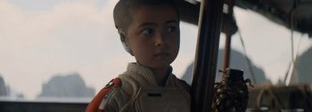 Movie still from “The Creator” (2023), directed by Gareth Edwards – A young boy with a helmet on his head; Close Up shot, Over the shoulder angle