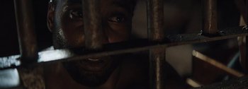 Movie still from “The Creator” (2023), directed by Gareth Edwards – A person behind a metal fence; Extreme Close Up shot, Overhead angle