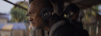 Movie still from “The Creator” (2023), directed by Gareth Edwards – An older man with a helmet on his head; Close Up shot, Over the shoulder angle