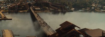 Movie still from “The Creator” (2023), directed by Gareth Edwards – People walking across a bridge over a body of water; Extreme Wide shot, High angle