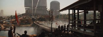 Movie still from “The Creator” (2023), directed by Gareth Edwards – A group of people walking across a bridge over a river; Extreme Wide shot, Low angle