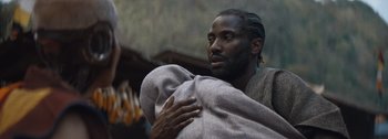 Movie still from “The Creator” (2023), directed by Gareth Edwards – A man holding a blanket in his arms; Close Up shot, Low angle