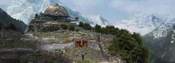 Movie still from “The Creator” (2023), directed by Gareth Edwards – An image of a man standing in front of a building in the middle of a mountain; Extreme Wide shot, High angle