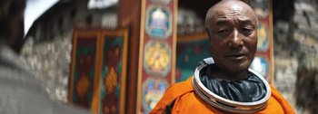 Movie still from “The Creator” (2023), directed by Gareth Edwards – A man wearing an orange suit and a black helmet; Close Up shot, Low angle
