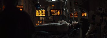 Movie still from “The Creator” (2023), directed by Gareth Edwards – An operating room with a person lying on a table; Wide shot, Low angle