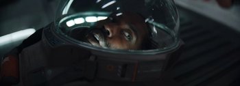 Movie still from “The Creator” (2023), directed by Gareth Edwards – A man's face as he sits in a space helmet; Close Up shot, Overhead angle