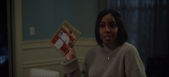 Movie still from “The Curse of Bridge Hollow” (2022), directed by Jeff Wadlow – A woman holding up a picture of herself and a man; Close Up shot, Over the shoulder angle