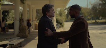 Movie still from “The Curse of Bridge Hollow” (2022), directed by Jeff Wadlow – Two men are shaking hands in front of a building; Medium shot, Over the shoulder angle
