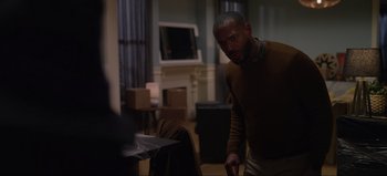 Movie still from “The Curse of Bridge Hollow” (2022), directed by Jeff Wadlow – A man standing in a living room next to a fireplace; Medium shot, Over the shoulder angle