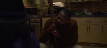 Movie still from “The Curse of Bridge Hollow” (2022), directed by Jeff Wadlow – A man holding a broom in a kitchen; Medium shot, Over the shoulder angle