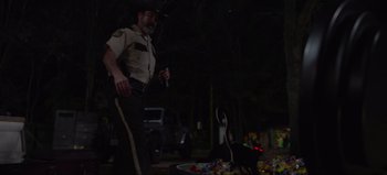 Movie still from “The Curse of Bridge Hollow” (2022), directed by Jeff Wadlow – A police officer standing in front of a fire hydrant at night; Medium shot, Over the shoulder angle