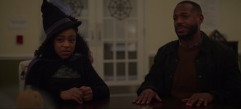 Movie still from “The Curse of Bridge Hollow” (2022), directed by Jeff Wadlow – A man and a woman sitting at a table in front of a window; Medium shot, Over the shoulder angle