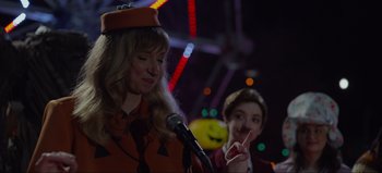 Movie still from “The Curse of Bridge Hollow” (2022), directed by Jeff Wadlow – A woman wearing a hat is speaking at a microphone; Close Up shot, Over the shoulder angle
