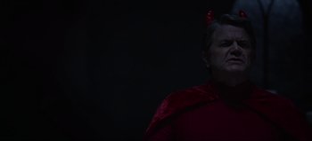 Movie still from “The Curse of Bridge Hollow” (2022), directed by Jeff Wadlow – A man in a red outfit with a red bow on his head; Close Up shot, Over the shoulder angle