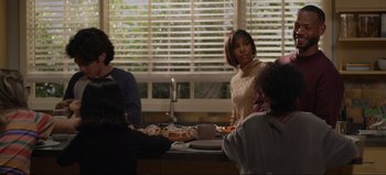 Movie still from “The Curse of Bridge Hollow” (2022), directed by Jeff Wadlow – A group of people sitting at a table with plates of food; Medium shot, Over the shoulder angle