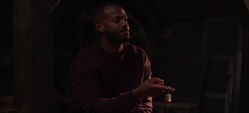 Movie still from “The Curse of Bridge Hollow” (2022), directed by Jeff Wadlow – A man in a red shirt is holding a cigarette; Medium shot, Over the shoulder angle