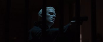 Movie still from “The Da Vinci Code” (2006), directed by Ron Howard – A man in a black jacket behind bars in a dark room; Close Up shot, Low angle