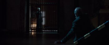 Movie still from “The Da Vinci Code” (2006), directed by Ron Howard – A man in a black suit standing in front of a gate; Wide shot, Over the shoulder angle
