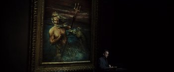 Movie still from “The Da Vinci Code” (2006), directed by Ron Howard – A man sitting in front of a painting of poseidon; Medium shot, Low angle