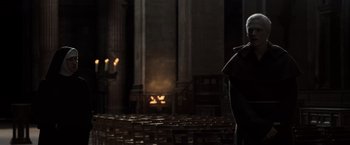 Movie still from “The Da Vinci Code” (2006), directed by Ron Howard – A man standing in a large room with candles in the background; Wide shot, Low angle