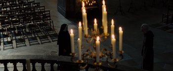 Movie still from “The Da Vinci Code” (2006), directed by Ron Howard – A nun in front of a chandelier with candles; Wide shot, High angle