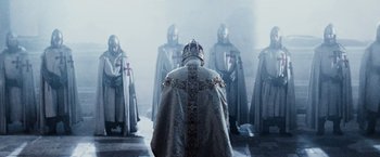 Movie still from “The Da Vinci Code” (2006), directed by Ron Howard – A group of men dressed as knights standing in front of a priest; Medium shot, Over the shoulder angle