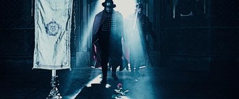 Movie still from “The Da Vinci Code” (2006), directed by Ron Howard – A man in a mask walking down a hallway; Wide shot, Low angle