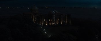 Movie still from “The Da Vinci Code” (2006), directed by Ron Howard – A large building lit up at night with lights on it; Extreme Wide shot, High angle