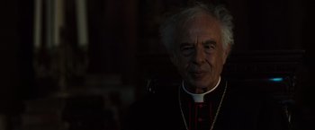 Movie still from “The Da Vinci Code” (2006), directed by Ron Howard – An older man wearing a priest's outfit; Close Up shot, Over the shoulder angle