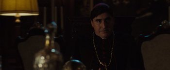 Movie still from “The Da Vinci Code” (2006), directed by Ron Howard – A man in a priest's outfit sitting in a chair; Close Up shot, Over the shoulder angle