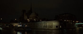 Movie still from “The Da Vinci Code” (2006), directed by Ron Howard – A boat in a body of water next to a building at night; Extreme Wide shot, High angle