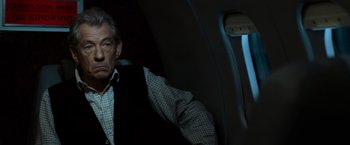 An older man sitting on a plane looking out the window