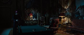 Movie still from “The Da Vinci Code” (2006), directed by Ron Howard – A man sitting in a chair next to a pool table; Wide shot, High angle