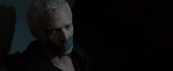 Movie still from “The Da Vinci Code” (2006), directed by Ron Howard – A man with his mouth taped shut is in the dark; Close Up shot, High angle