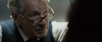 Movie still from “The Da Vinci Code” (2006), directed by Ron Howard – An older man wearing glasses looking at the camera; Close Up shot, Over the shoulder angle