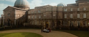 Movie still from “The Da Vinci Code” (2006), directed by Ron Howard – Two people standing in front of an old building with a car; Extreme Wide shot, High angle