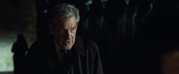 Movie still from “The Da Vinci Code” (2006), directed by Ron Howard – An older man in a black coat and a checkered shirt; Close Up shot, Over the shoulder angle